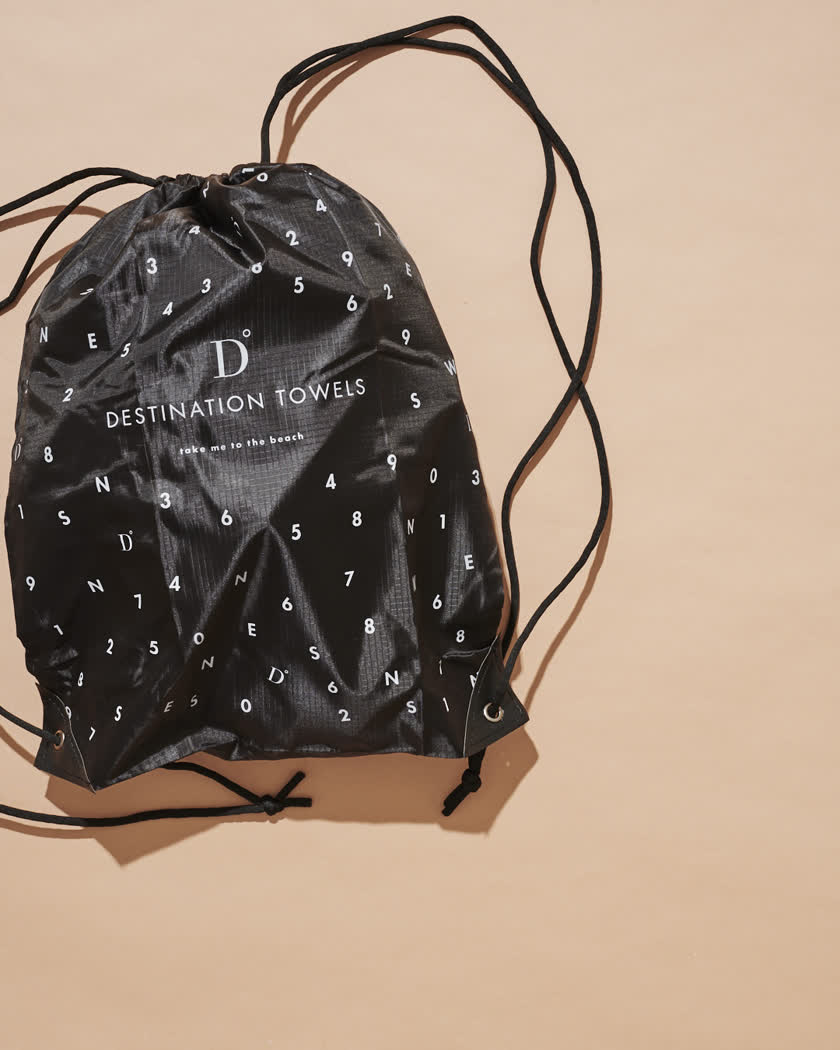 The included black drawstring backpack with the towel packed inside
